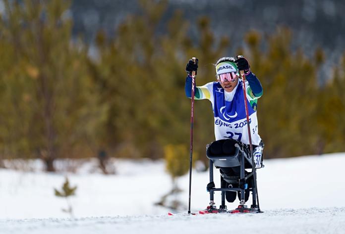 A female Para cross-country skier competes in a sit-ski
